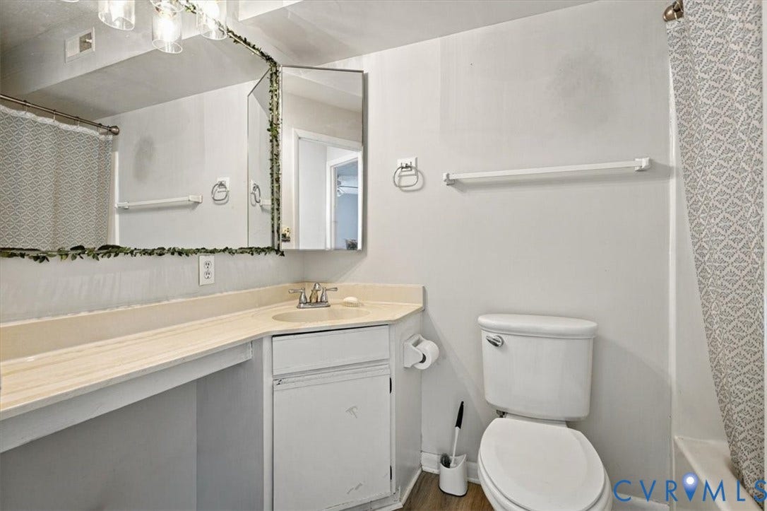Bathroom featuring an extended solid-surface vanity, integrated sink basin, tri-panel mirrored medicine cabinet, and wall-mounted light fixture