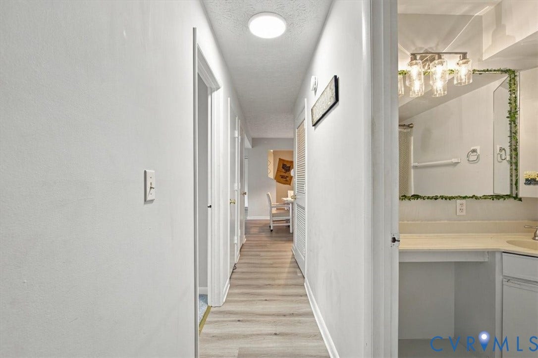 Hallway featuring wood-finish flooring, flush-mount ceiling lighting, and multiple interior doors