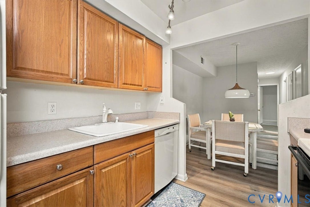 Kitchen featuring wood cabinetry, stone-finish countertops, integrated dishwasher, and recessed track lighting