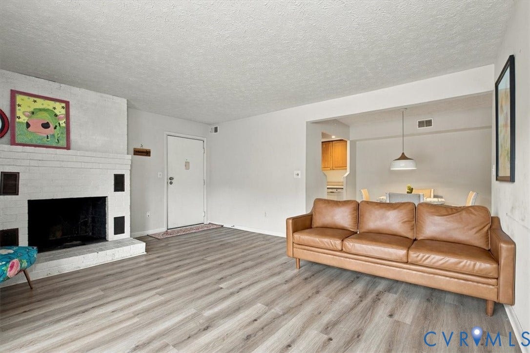 Living area featuring wood-finish flooring, a painted brick fireplace, and a dome pendant light fixture