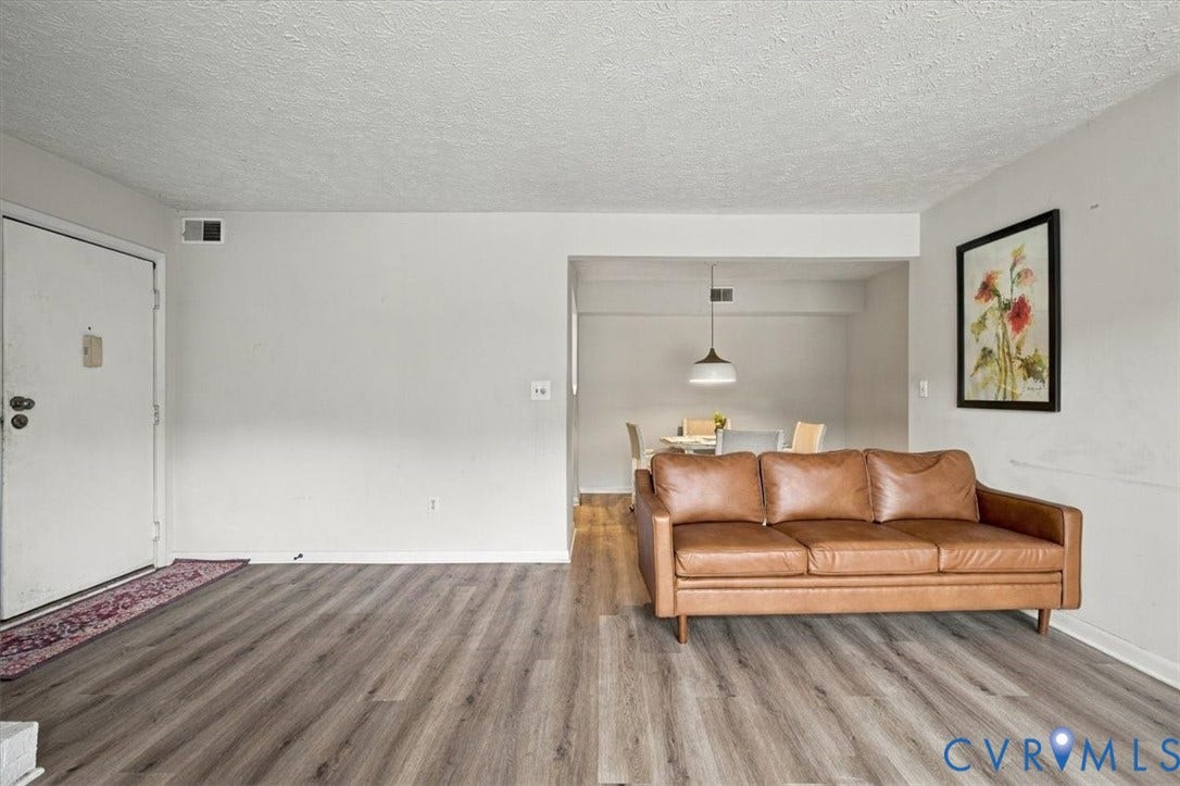 Open-concept interior featuring wood-finish flooring, a textured ceiling, and a dome-style pendant light fixture