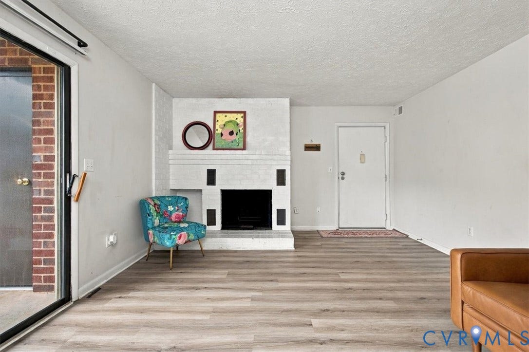 Painted brick fireplace, wood-finish flooring, and sliding glass door