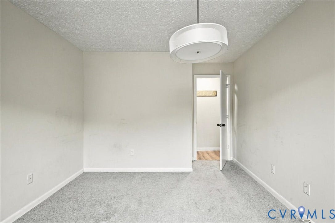 Room featuring neutral wall tones, gray carpeting, and a contemporary drum-style pendant light fixture
