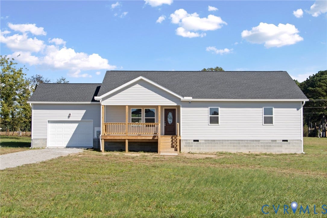 79 Dixie Drive, Mathews, VA 23050 Single-story residence featuring light-toned vinyl siding, an attached garage, a covered front porch with wood railings, and a shingled gable roof