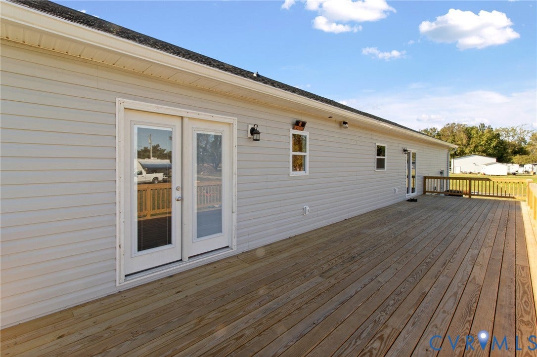 79 Dixie Drive, Mathews, VA 23050 Expansive wooden deck featuring horizontal siding, glass-paned double doors, and wood-slat railings