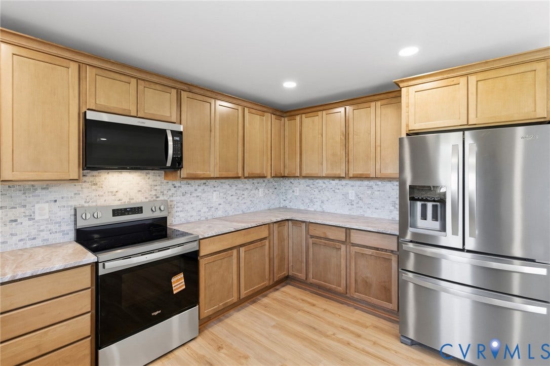 79 Dixie Drive, Mathews, VA 23050 Kitchen featuring light wood-finish cabinetry, stone-patterned countertops, a multi-tone tile backsplash, and stainless steel appliances