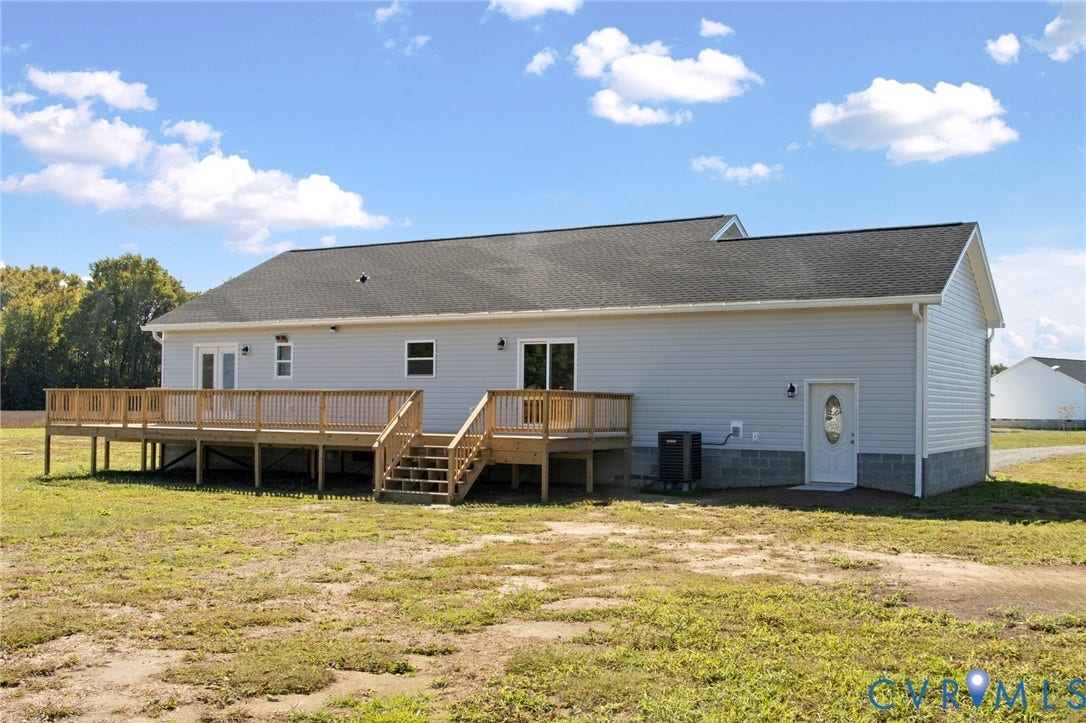 79 Dixie Drive, Mathews, VA 23050 Exterior featuring light-gray horizontal siding, a composite shingle roof, a raised wood deck with balustrades, and a white entry door with an oval glass insert
