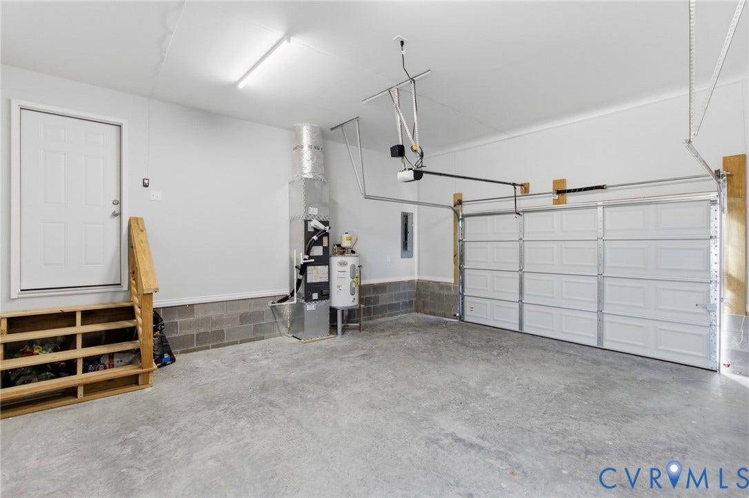 79 Dixie Drive, Mathews, VA 23050 Garage interior featuring a concrete floor, sectional overhead door, built-in wooden staircase, and exposed HVAC system