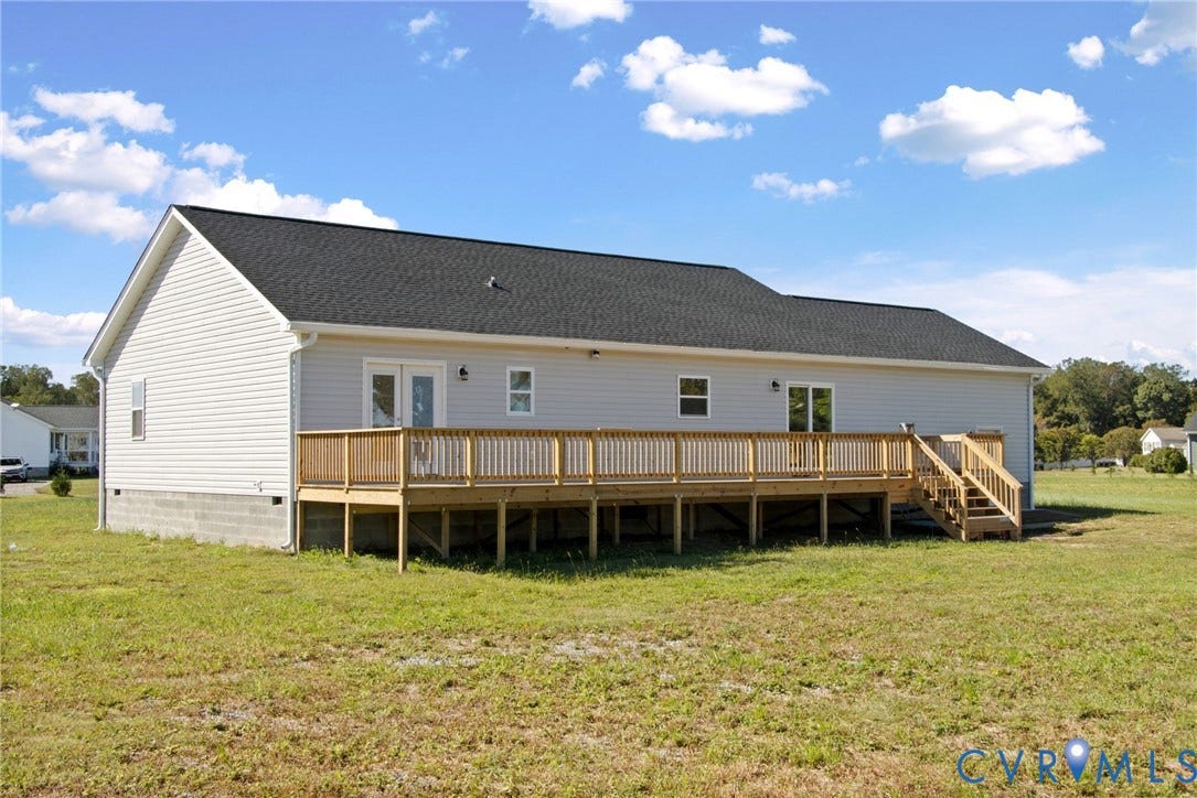 79 Dixie Drive, Mathews, VA 23050 Exterior featuring light-colored horizontal siding, a gabled roof, a wood-framed deck with stairs, and multiple glass-panel doors