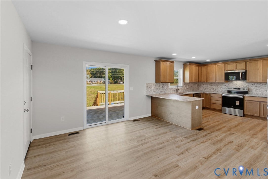 79 Dixie Drive, Mathews, VA 23050 Kitchen featuring wood-finish cabinetry, stone-look countertops, stainless steel appliances, sliding glass doors, and light wood-finish flooring