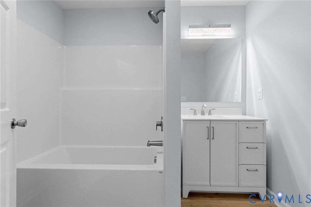 79 Dixie Drive, Mathews, VA 23050 Bathroom featuring a white vanity with drawers, a rectangular mirror with integrated light fixture, and a tub-shower combination with a showerhead and metal faucet