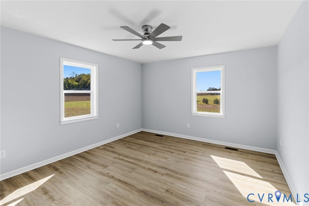 79 Dixie Drive, Mathews, VA 23050 Room featuring wood-finish flooring, neutral wall paint, two dual-pane windows, and a central ceiling fan with integrated lighting