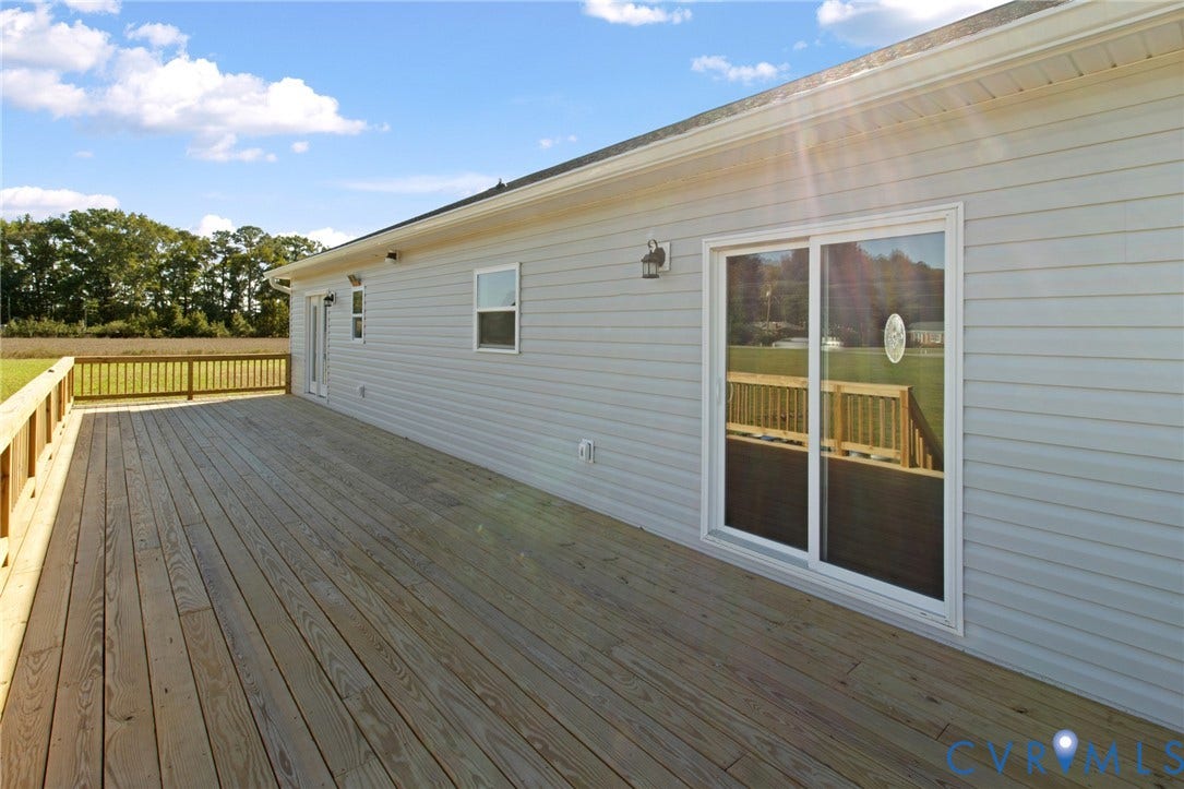 79 Dixie Drive, Mathews, VA 23050 Expansive wooden deck featuring horizontal siding, sliding glass doors, and wooden perimeter railing