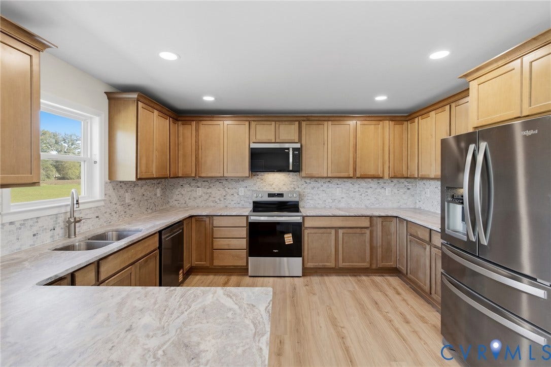 79 Dixie Drive, Mathews, VA 23050 Kitchen featuring natural-finish wood cabinetry, stone-patterned countertops, mosaic tile backsplash, stainless steel appliances, and wood-finish flooring