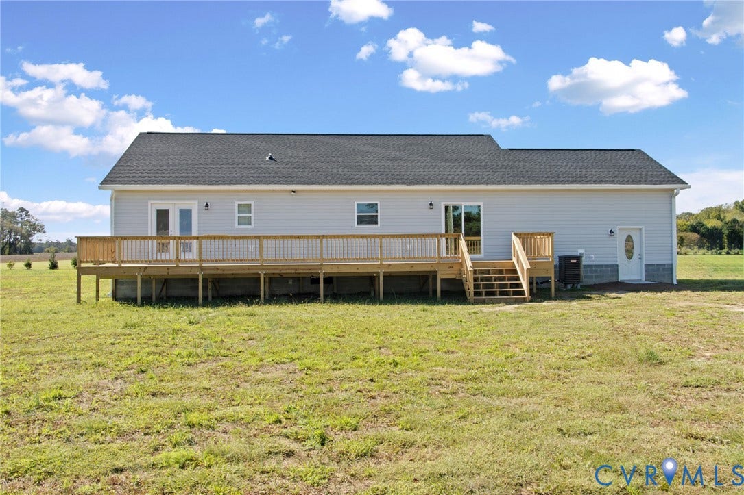 79 Dixie Drive, Mathews, VA 23050 Exterior featuring grey vinyl siding, shingle roofing, a sprawling elevated wood deck with railing, and multiple access points including French doors and a sliding glass door