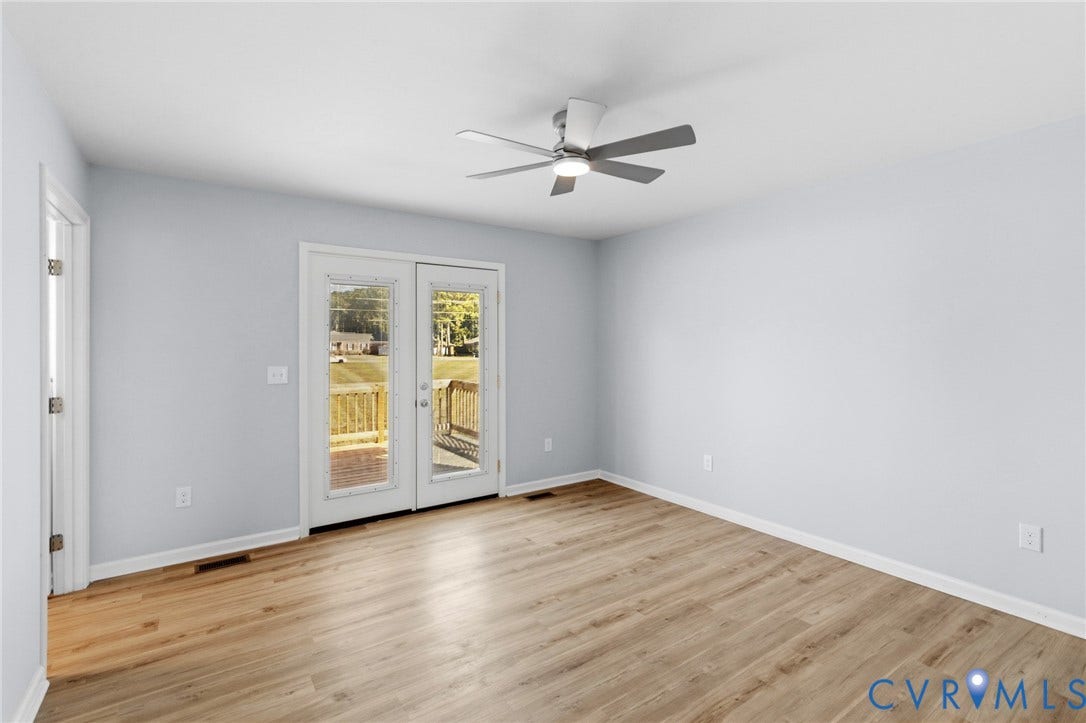 79 Dixie Drive, Mathews, VA 23050 Neutral-toned room with wood-finish flooring, a multi-blade ceiling fan with integrated light, and glass-paneled double doors providing exterior access