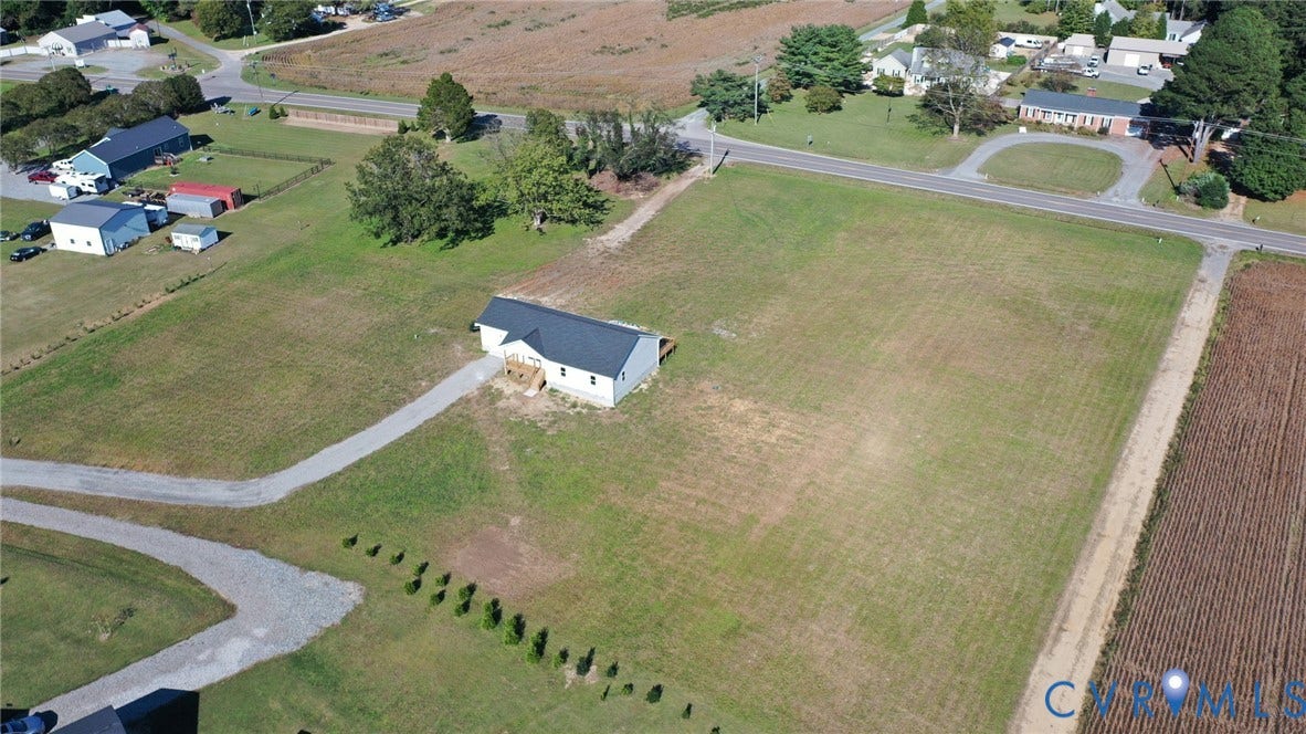 79 Dixie Drive, Mathews, VA 23050 Single-story residence featuring a dark metal roof, expansive open acreage, and a long gravel driveway