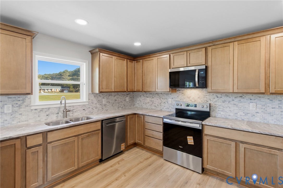 79 Dixie Drive, Mathews, VA 23050 Kitchen featuring shaker-style light wood cabinetry, stone-patterned countertops, a mosaic tile backsplash, stainless steel appliances, and wood-finish flooring