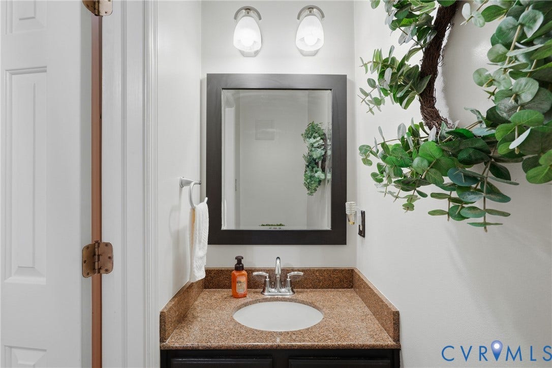14800 Highberry Woods Drive, Midlothian, VA 23112 Vanity featuring a stone-composite countertop with an undermount sink, dark-finish cabinetry, a framed mirror, and dual wall-mounted light fixtures