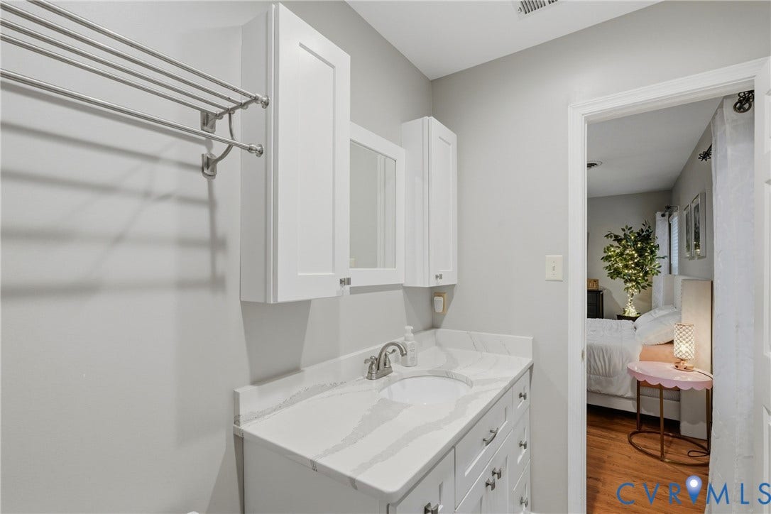 14800 Highberry Woods Drive, Midlothian, VA 23112 Bathroom featuring a white vanity cabinet with stone-patterned countertop, integrated undermount sink, wall-mounted storage cabinetry, and polished metal hardware