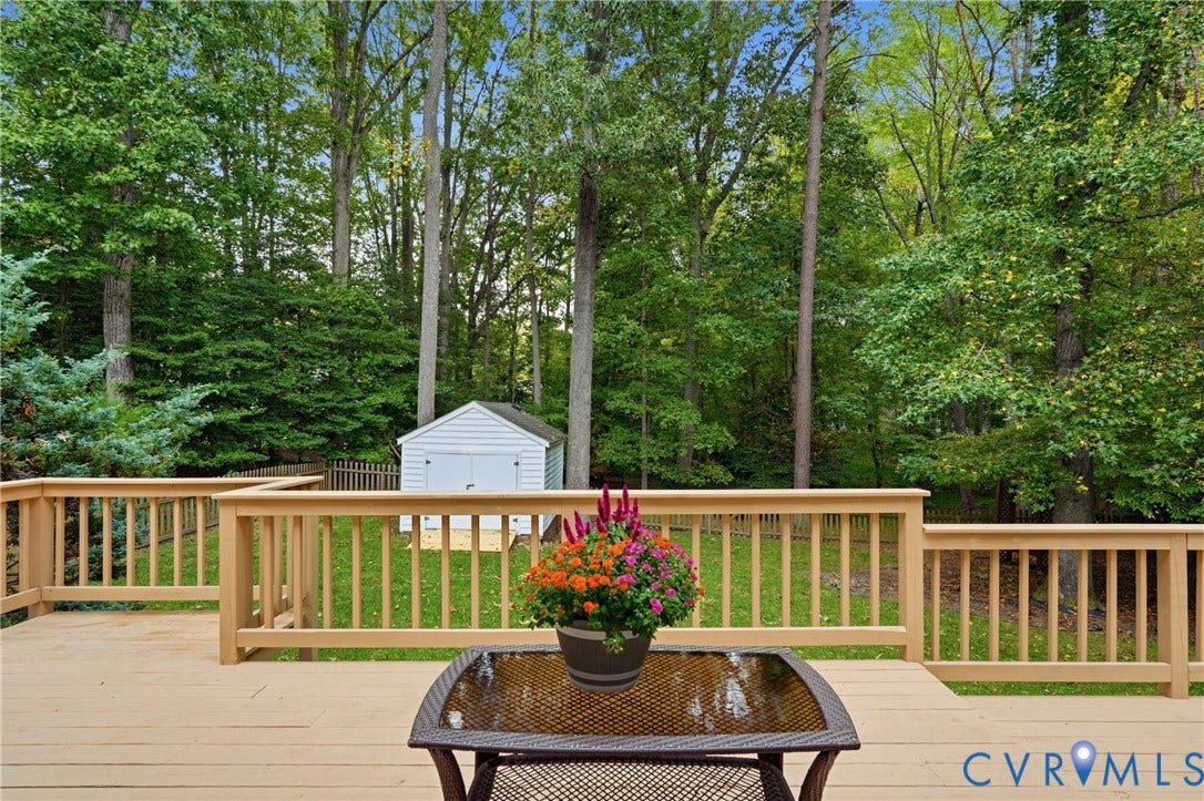 14800 Highberry Woods Drive, Midlothian, VA 23112 Raised wood deck with balustrades, expansive lawn, detached storage structure, and perimeter fencing set against a wooded backdrop