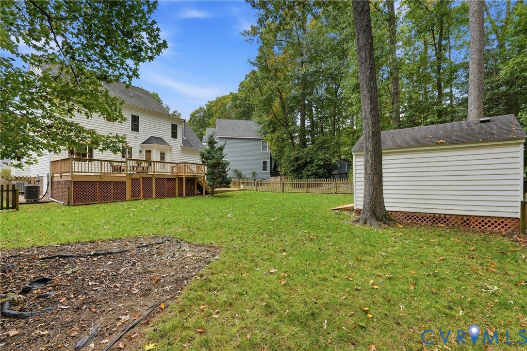 14800 Highberry Woods Drive, Midlothian, VA 23112 Backyard featuring a raised wooden deck, lattice skirting, detached storage structure, and perimeter wood fencing surrounded by mature trees