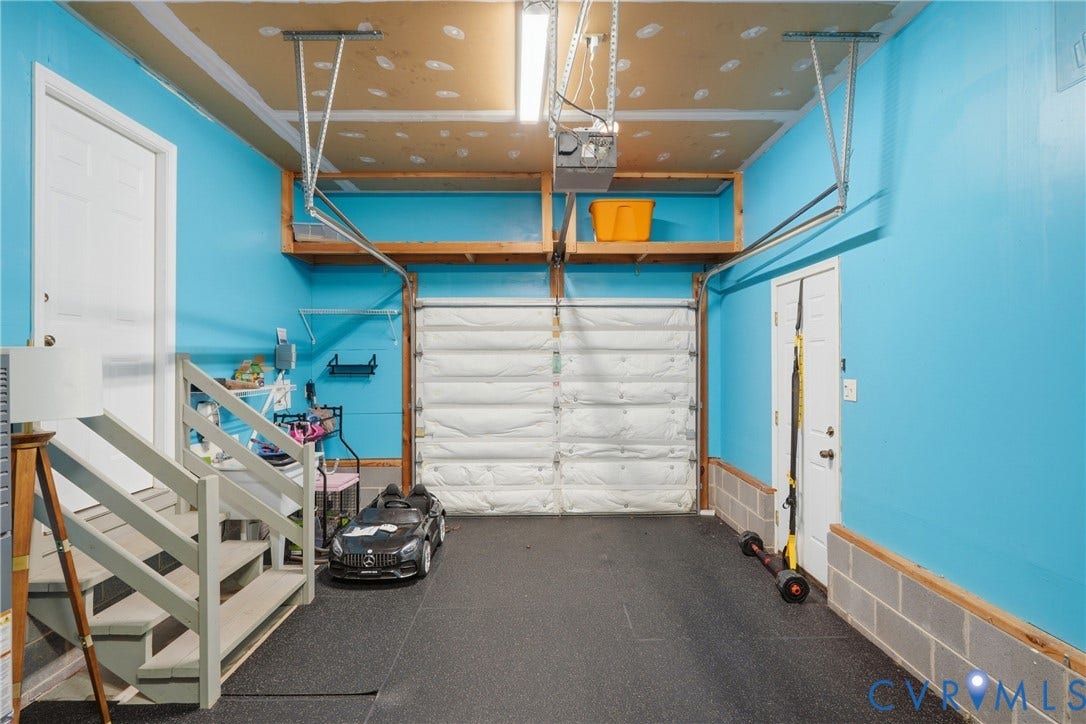 14800 Highberry Woods Drive, Midlothian, VA 23112 Garage featuring an insulated sectional door, overhead wood-frame storage shelving, dark textured flooring, and interior wooden staircase