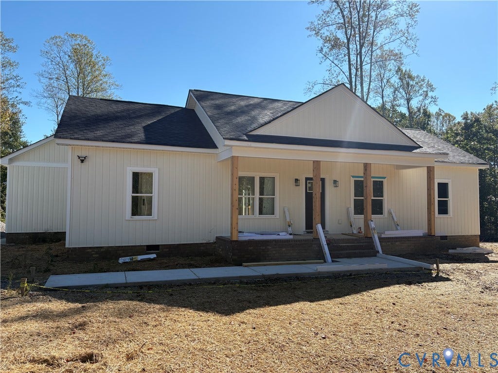 15205 Lebanon Road, Parson's Retreat, Disputanta, VA 23842 Single-story exterior featuring vertical light-toned siding, a covered front porch with timber-style support columns, brick foundation skirting, and a dark shingle roof
