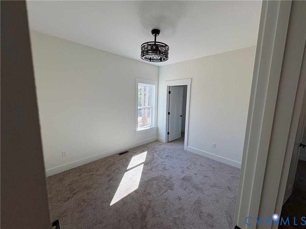 15205 Lebanon Road, Parson's Retreat, Disputanta, VA 23842 Neutral-toned interior room featuring wall-to-wall carpeting, a multi-panel door, and a circular drum-style ceiling light fixture
