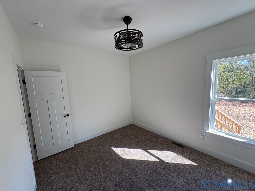 15205 Lebanon Road, Parson's Retreat, Disputanta, VA 23842 Neutral wall tones, carpeted flooring, multi-panel interior door with matte black hardware, and an architectural drum-style ceiling light fixture