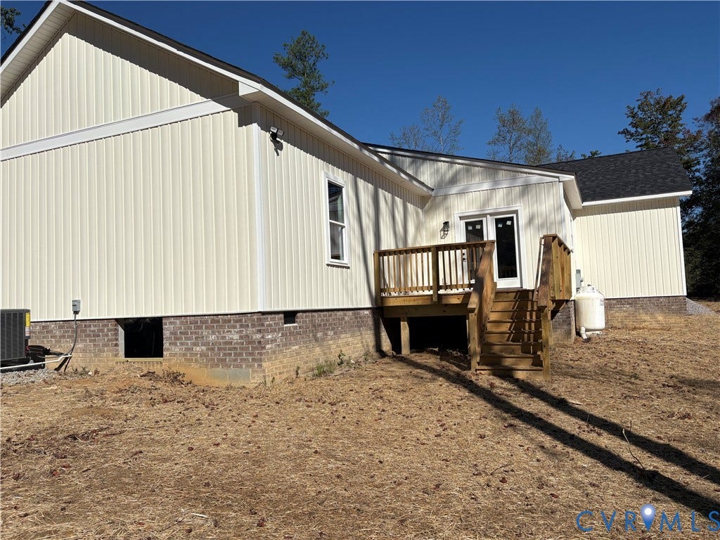 15205 Lebanon Road, Parson's Retreat, Disputanta, VA 23842 Exterior featuring vertical board-and-batten siding, a brick foundation, a wood deck with stairs, and a dark shingle roof