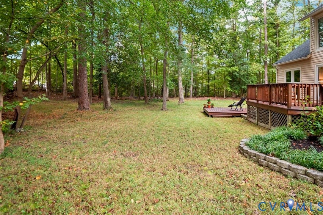 10209 Francill Court, North Chesterfield, VA 23236 Private backyard featuring mature trees, a raised wood deck, a secondary ground-level deck, and a stone garden border