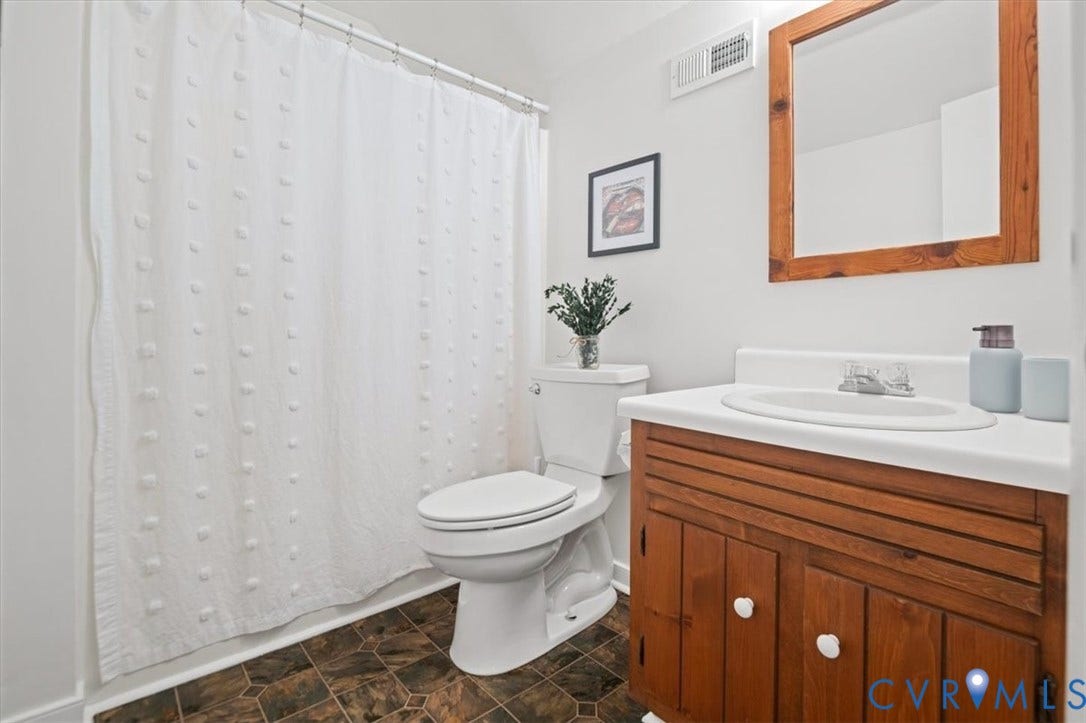 10209 Francill Court, North Chesterfield, VA 23236 Bathroom featuring a wooden vanity, integrated sink, matching wooden-framed mirror, and patterned tile flooring