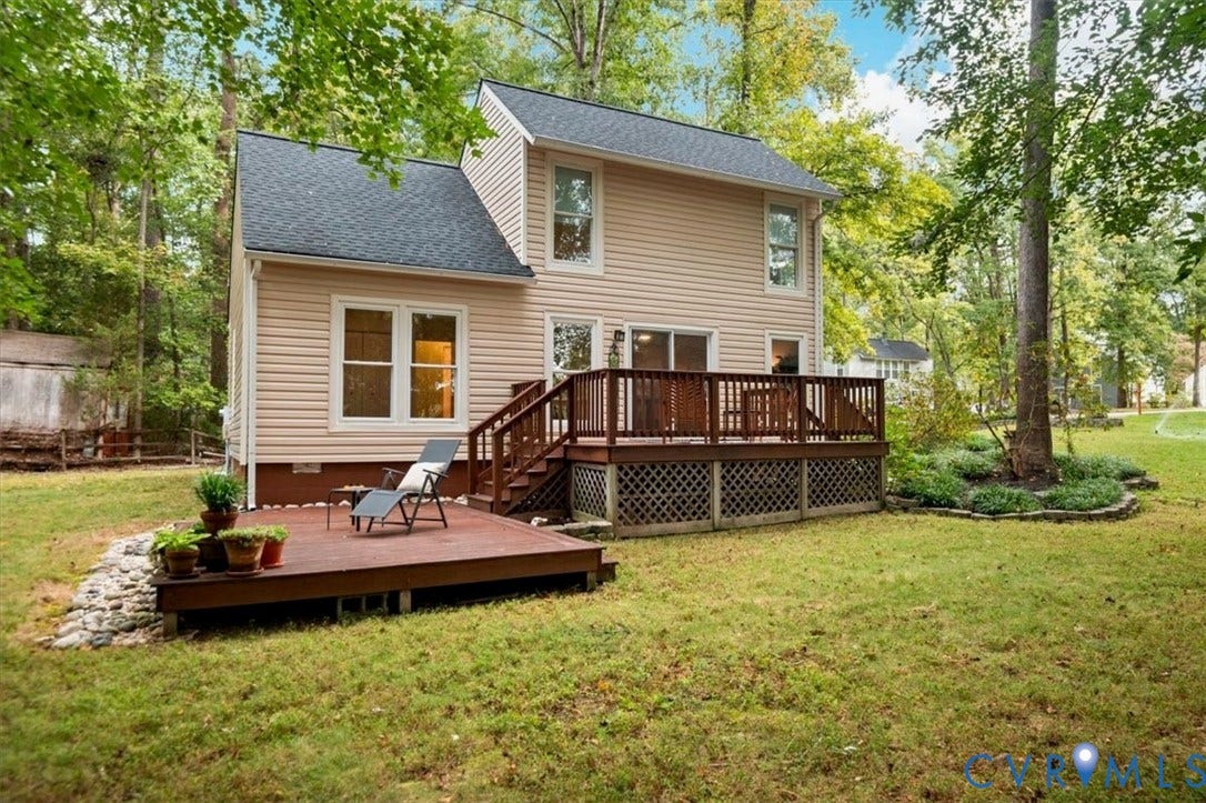 10209 Francill Court, North Chesterfield, VA 23236 Two-story residence featuring light-toned horizontal siding, a multi-level wood deck, lattice skirting, and a stone-lined drainage area