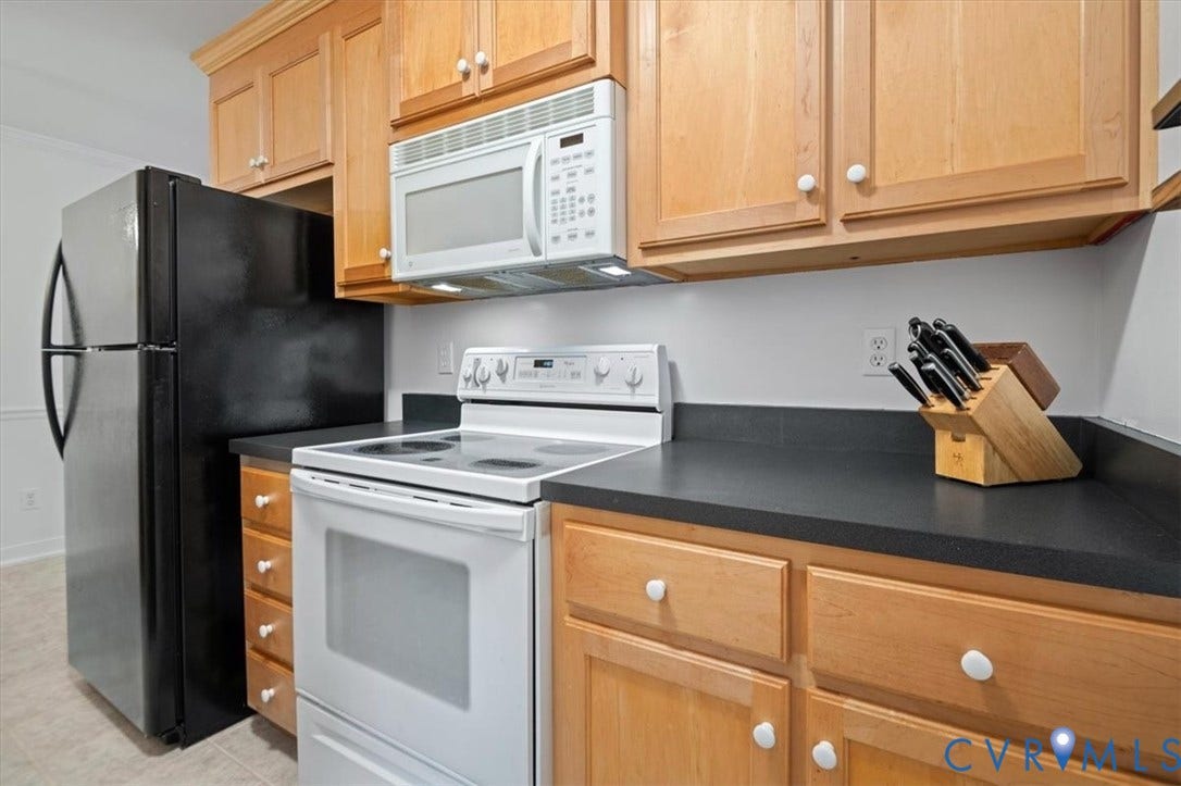 10209 Francill Court, North Chesterfield, VA 23236 Kitchen featuring light-finish wood cabinetry, matte black countertops, a white electric range, a white over-the-range microwave, and a black refrigerator