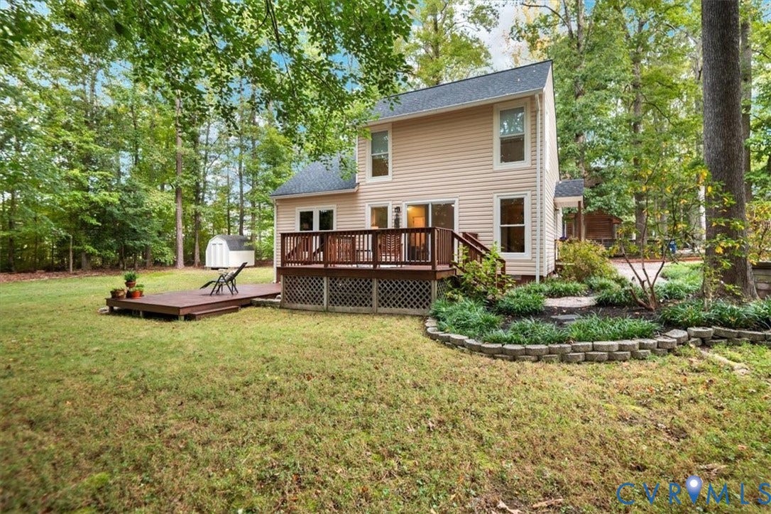 10209 Francill Court, North Chesterfield, VA 23236 Two-story exterior featuring light-toned horizontal siding, a multi-level wood deck with lattice skirting, and a curved stone-bordered landscaping bed