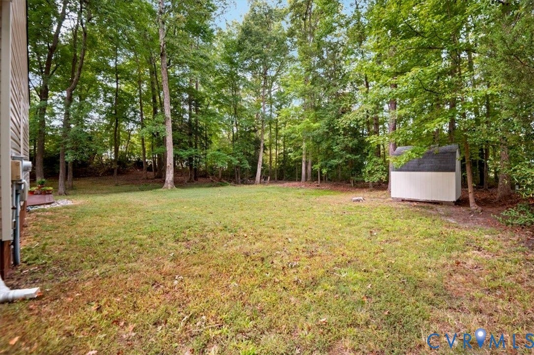 10209 Francill Court, North Chesterfield, VA 23236 Backyard featuring a grass lawn, mature trees, and a detached storage shed