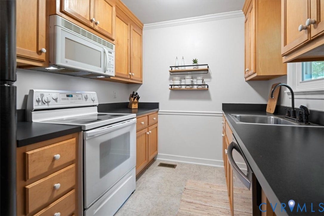 10209 Francill Court, North Chesterfield, VA 23236 Kitchen featuring wood cabinetry, black solid-surface countertops, white electric range with built-in microwave, and stainless steel sink with a matte black faucet