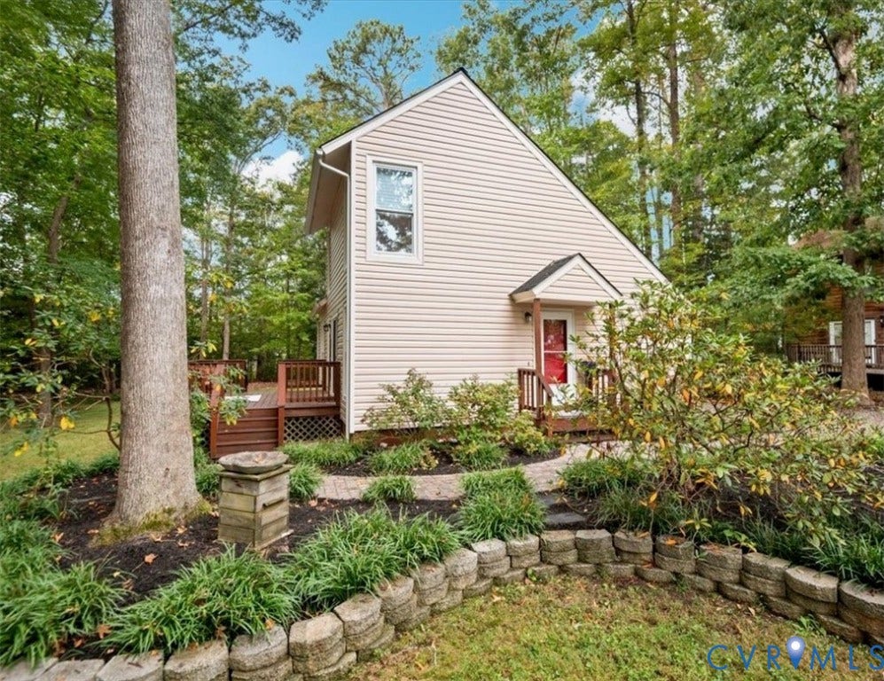 10209 Francill Court, North Chesterfield, VA 23236 Exterior featuring light-toned horizontal siding, a raised wooden deck, stone-block retaining walls, and a paved stone walkway surrounded by established landscaping