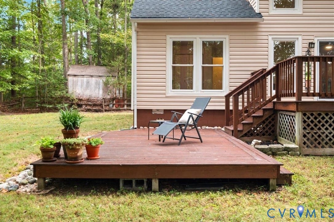 10209 Francill Court, North Chesterfield, VA 23236 Ground-level wooden deck featuring a raised wooden platform and stairs with lattice skirting, light-toned horizontal siding, and an expansive rear yard with mature trees