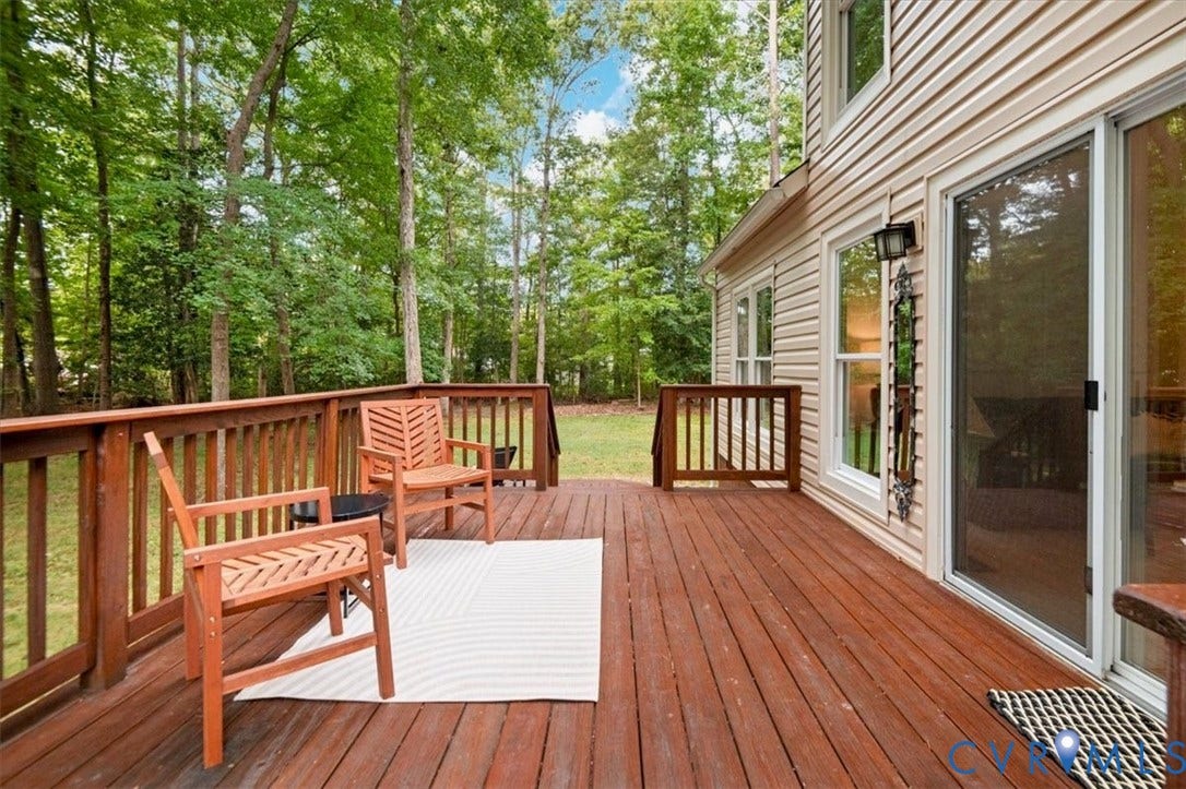 10209 Francill Court, North Chesterfield, VA 23236 Raised wooden deck featuring horizontal railings, light-colored vinyl siding, sliding glass doors, and exterior wall-mounted lighting