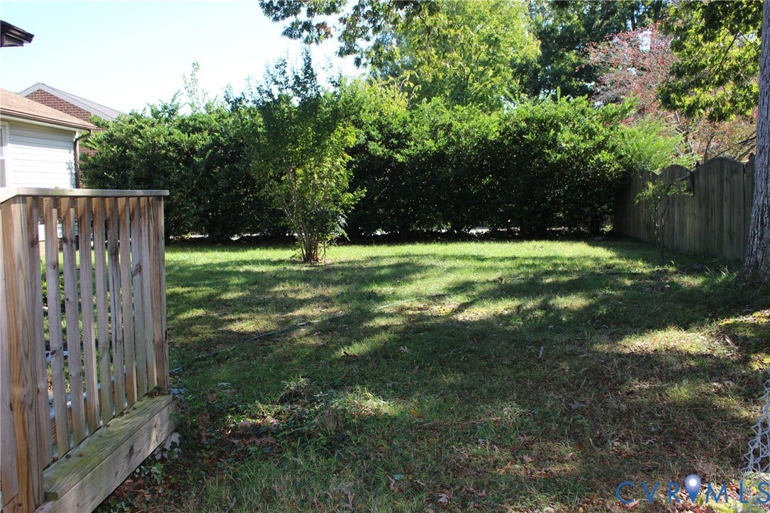 905 Williamsburg Road, Colonial Heights, VA 23834 Backyard space featuring a wooden deck, mature perimeter hedging, and wood fencing
