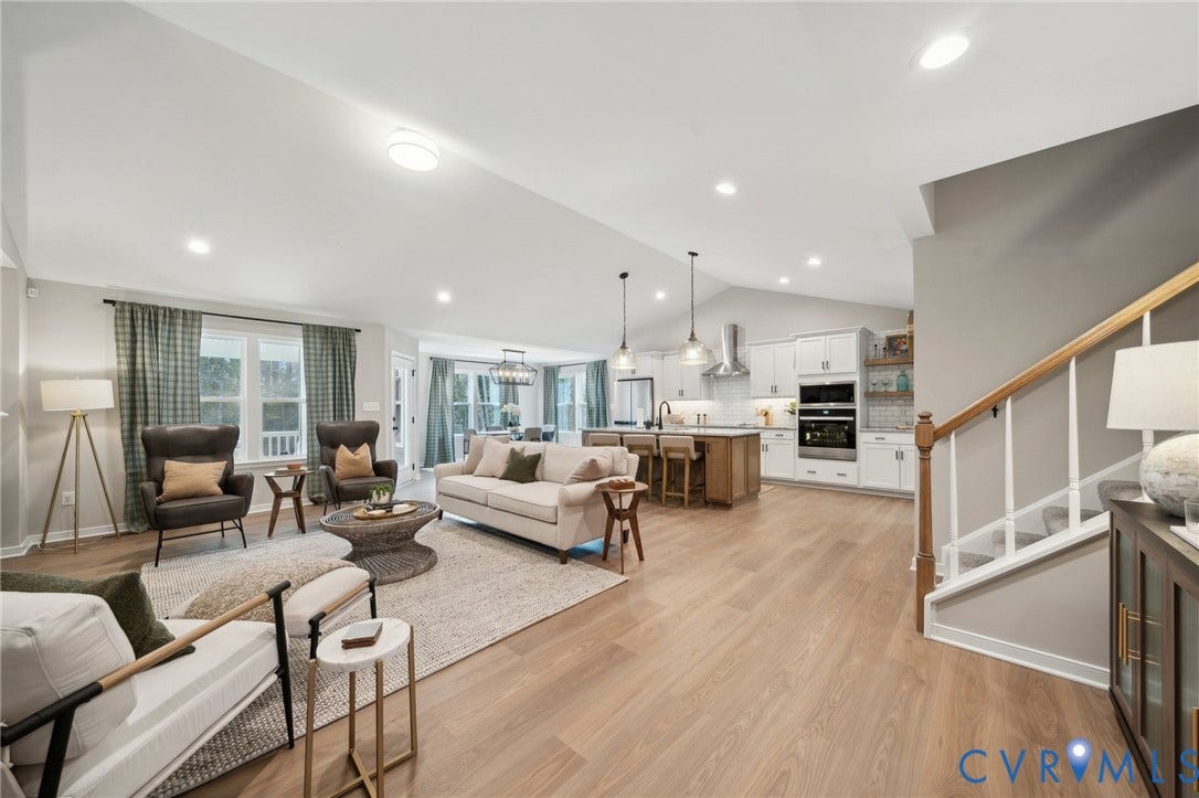 Open-concept living space featuring vaulted ceilings, wood-finish flooring, recessed lighting, and a kitchen equipped with an island and built-in appliances
