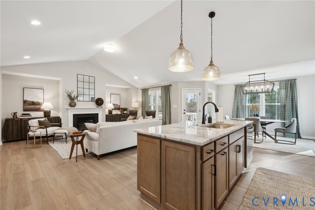 Vaulted ceilings, wood-finish flooring, kitchen island with stone countertop, matte black faucet, and fireplace with mantle