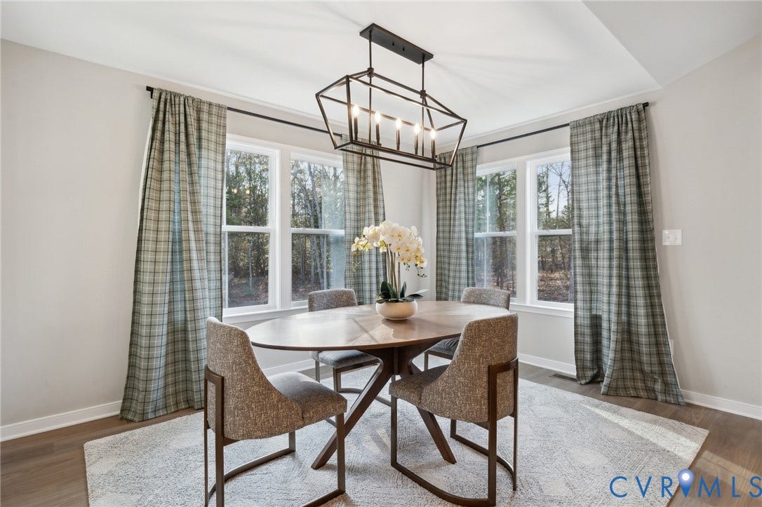 Tray ceiling, geometric matte black chandelier, multiple large windows, and wood-finish flooring