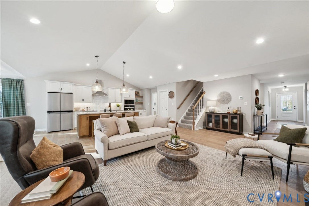Open-concept interior featuring vaulted ceilings, recessed lighting, wood-finish flooring, a kitchen island with pendant lighting, and a staircase with a wooden handrail