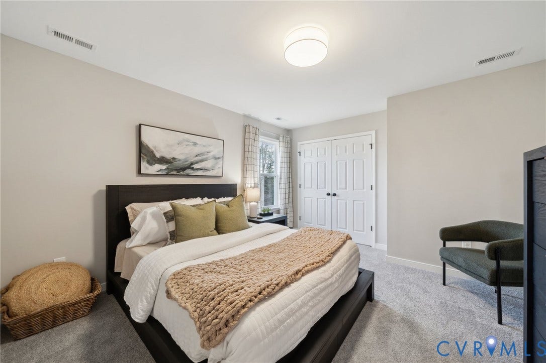 Neutral-toned walls, carpeted flooring, double-door closet with paneled detailing, and centered drum-style ceiling lighting
