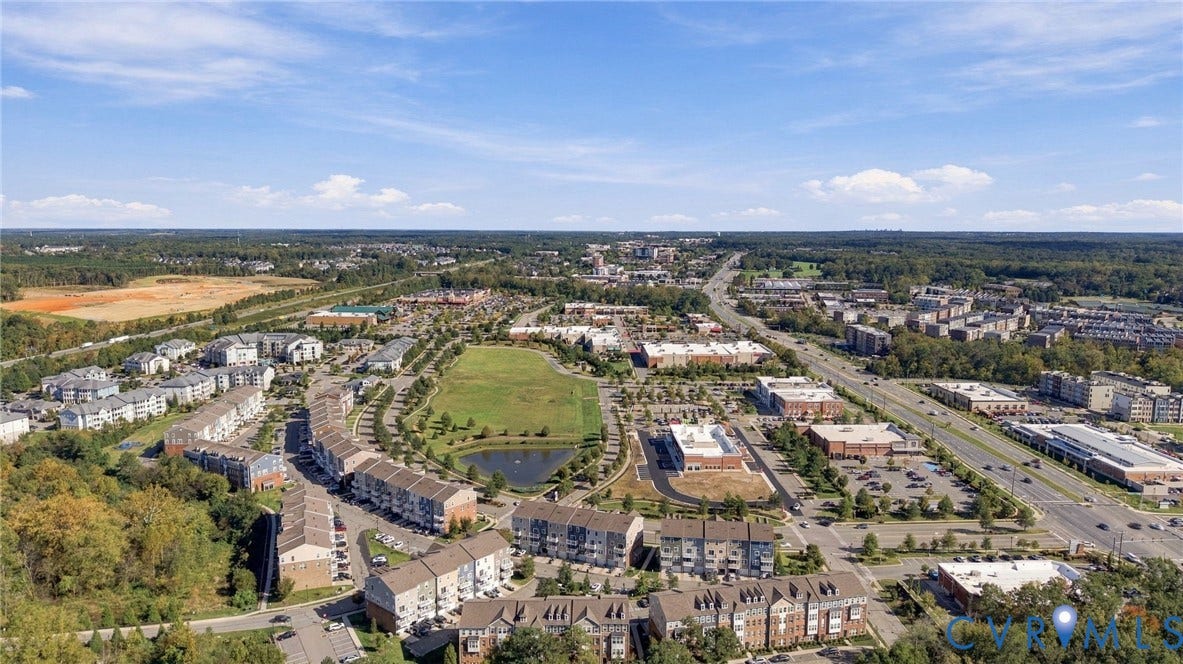 4223 Saunders Tavern Trail, #A, Henrico, VA 23233 Aerial perspective showcasing a multi-building residential community featuring planned green space, an integrated retention pond, and paved pedestrian walkways