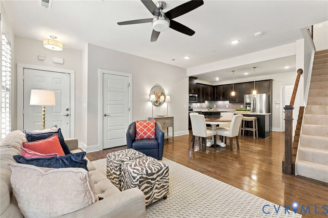4223 Saunders Tavern Trail, #A, Henrico, VA 23233 Open-concept interior featuring wood-finish flooring, dark cabinetry with stainless steel appliances, a center island with pendant lighting, a ceiling fan, and a staircase with a wooden handrail