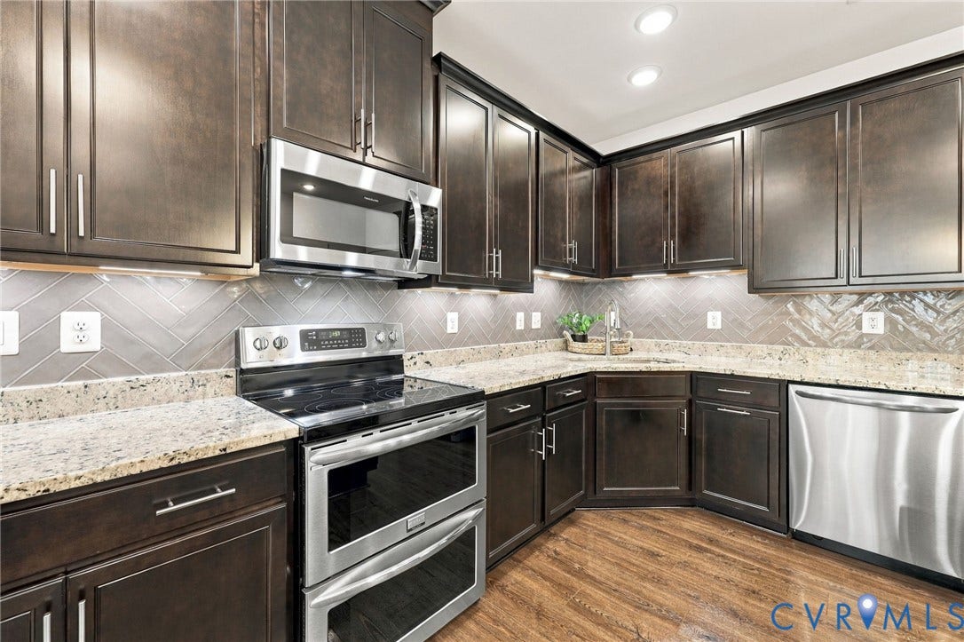 4223 Saunders Tavern Trail, #A, Henrico, VA 23233 Kitchen featuring dark-finish cabinetry, stone-surface countertops, herringbone-pattern tile backsplash, stainless steel appliances, and wood-finish flooring